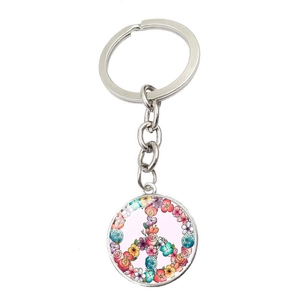 Detailed close-up of a silver peace sign keychain with a colorful floral pattern inlay