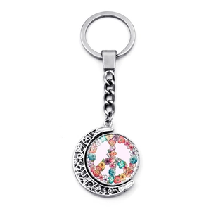 Silver rotating moon keychain with floral peace sign pendant on white background