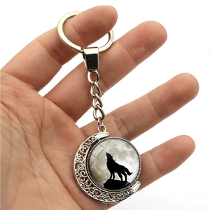 Close-up of howling wolf pendant on rotating moon keychain made of silver metal