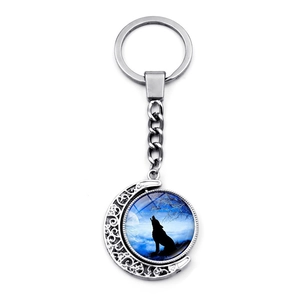 Close-up of rotating moon keychain with howling wolf glass gem and silver metal frame