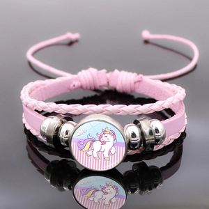 Détail macro du bracelet multicouche en cuir tressé rose avec breloque licorne