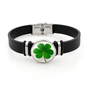 Close-up of black leather bracelet with green four-leaf clover glass cabochon charm