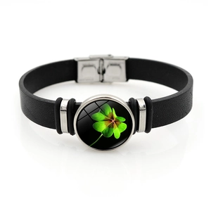 Close-up of black leather bracelet with green clover glass charm and silver snap clasp