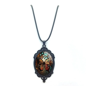 Close-up of vintage oval butterfly pendant with glass dome and black braided cord