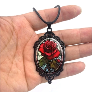 Vintage oval pendant necklace featuring a red rose pattern and black filigree metal frame