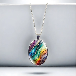Macro detail of oval pendant featuring abstract rainbow fluid patterns and gold glitter accents