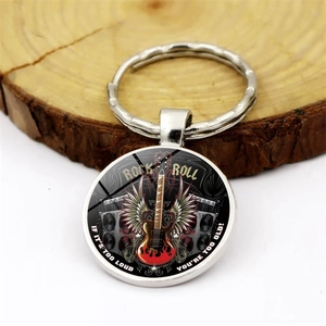 Rock and roll electric guitar glass dome keychain with silver alloy base on wood background