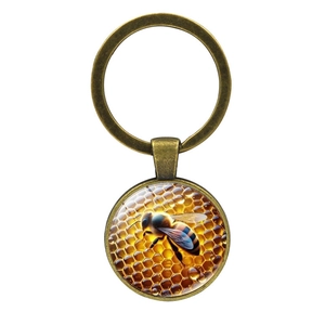 Vintage bronze keychain with a round glass bee and honeycomb pendant on a white background