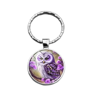 Macro detail of owl pendant keychain with purple illustration and clear glass dome