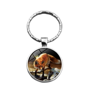 Metal key ring featuring a round glass cabochon with a red fox in a forest scene