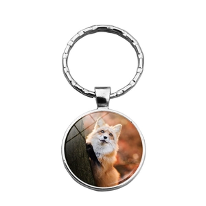 Silver metal keychain with a round glass pendant featuring a realistic red fox in nature