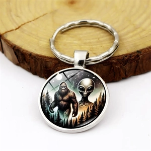 Detailed macro view of Bigfoot and UFO glass dome pendant on silver metal keychain