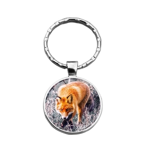 Detail of a silver metal keychain featuring a round glass pendant with a red fox image