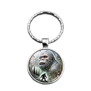 Detail of silver metal Bigfoot keychain with realistic forest illustration in a glass cabochon
