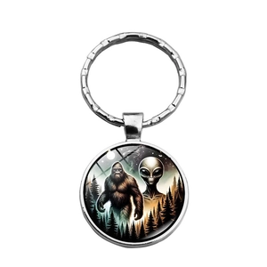 Detail of metal keychain with Bigfoot and Alien forest glass cabochon art design