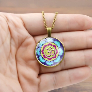 Gros plan d'un collier pendentif mandala Om en bronze avec un dôme en verre coloré