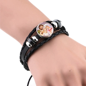 Detail view of multi-layer braided leather bracelet with Holy Family glass dome charm