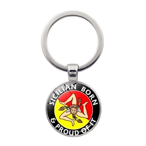 Close-up of Sicilian Trinacria relief keychain with red and yellow emblem on white background