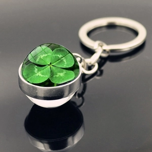 Silver four-leaf clover keychain with a green specimen in a double-sided glass ball