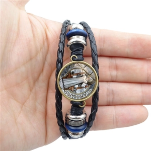 Nahaufnahme der St.-Benedikt-Medaille am mehrlagigen geflochtenen Lederarmband