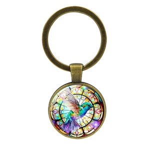 Portachiavi con colibrì in vetro e anello in metallo bronzo antico su sfondo bianco