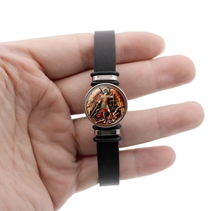 Detailed close-up of Saint Michael Archangel religious icon on black leather bracelet