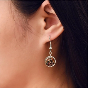 Gros plan de boucles d'oreilles Saint-Michel en argent sur modèle avec dôme en verre