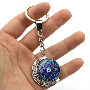 Close-up of evil eye moon keychain with rotating blue mandala pendant in hand