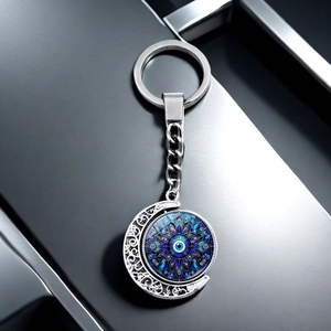 Rotating evil eye keychain with moon pendant in silver alloy on a dark metal background