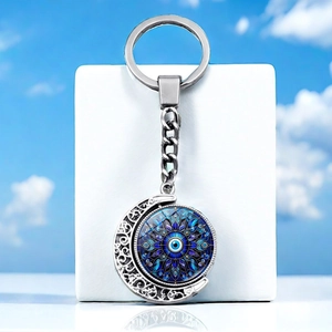 Detailed view of rotating crescent moon pendant with blue evil eye on a key chain
