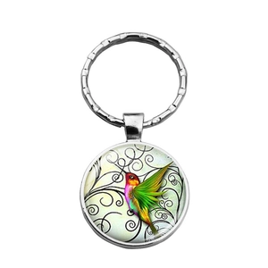 Detalle del llavero de colibrí en metal plateado con colgante de cabujón de vidrio color