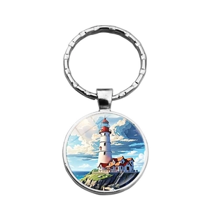 Close-up of circular metal keychain featuring a coastal lighthouse glass gem pendant