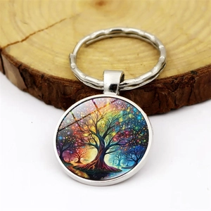 Colorful Tree of Life keychain with silver metal frame on a rustic wood background