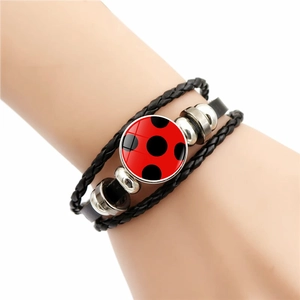 Close-up of multilayer leather bracelet with red and black polka dot glass charm and beads