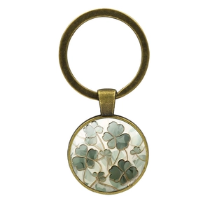 Vintage bronze four-leaf clover keychain with green glass dome charm on white background