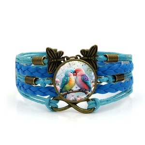 Détail du bracelet en cuir tressé avec lanières bleues et cabochon en verre inséparable