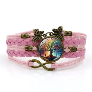 Détail du bracelet tressé rose avec pendentifs arbre de vie, papillon et symbole de l'infini