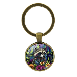 Antique bronze keychain featuring a round glass cabochon with colorful raccoon and floral art