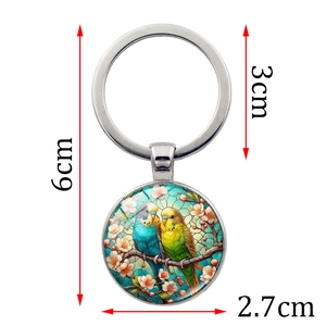 Creative metal keychain with two parrots on a branch inside a glass cabochon pendant