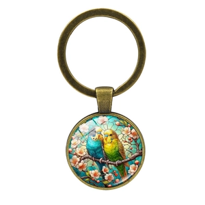 Vintage bronze keychain featuring two colorful parrots on a pink cherry blossom branch