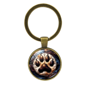 Macro view of bronze paw print glass cabochon pendant on a metal keychain ring