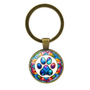Detail of vintage bronze keychain featuring a colorful cat paw print under glass dome