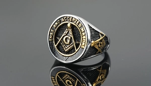 Macro shot of silver Masonic ring with gold G compass emblem and Free Masons text detail