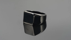 Vista macro di un anello a sigillo in acciaio inossidabile nero lucido con superficie quadra