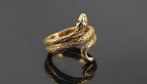 Dettaglio dell'anello a serpente dorato con scaglie e occhi in zircone rosso su nero