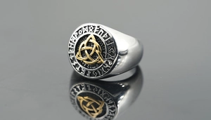 Macro detail of Viking signet ring with golden Triquetra symbol and Nordic runes engraving