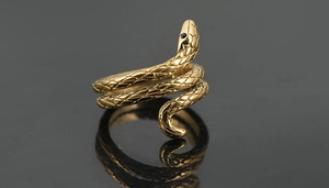 Dettaglio anello a serpente dorato con scaglie intrecciate e occhi di pietre nere