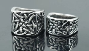 Gros plan de bagues rétro en acier avec motifs celtiques sur surface miroir noire