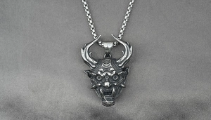 Dettaglio del ciondolo maschera Hannya vintage in stile industriale con catena in acciaio