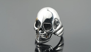 Macro shot of polished silver skull ring showing detailed metal texture and Gothic design